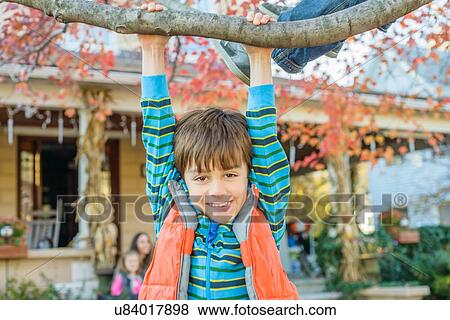 Stock Photo - Boy hanging on branch. Fotosearch