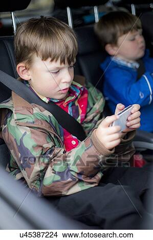 Boy in car using digital device View Large Photo Image Picture - Boy in car using digital device. Fotosearch