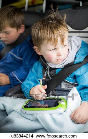 Boy in car with a digital device View Large Photo Image Picture - Boy in car with a digital device. Fotosearch