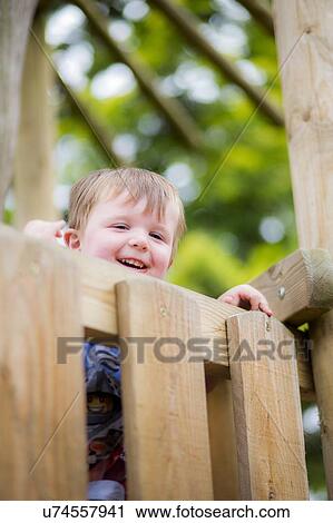 Stock Image - Boy peeking over fence. Fotosearch