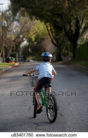Boy riding bicycle in middle of road View Large Photo Image Stock Image - Boy riding bicycle in middle of road. Fotosearch