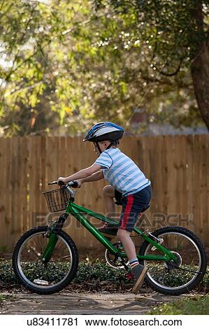 Boy riding bicycle past wooden fence View Large Photo Image Stock Image - Boy riding bicycle past wooden fence. Fotosearch