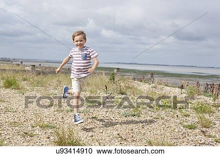 Stock Image - Boy running on the beach. Fotosearch
