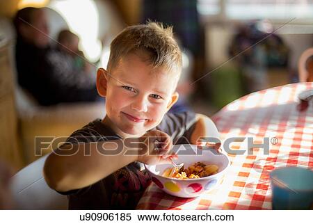 Stock Photography - Boy sitting at table eating a meal. Fotosearch