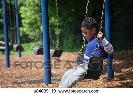 Stock Photo - Boy swinging on playground swing. Fotosearch