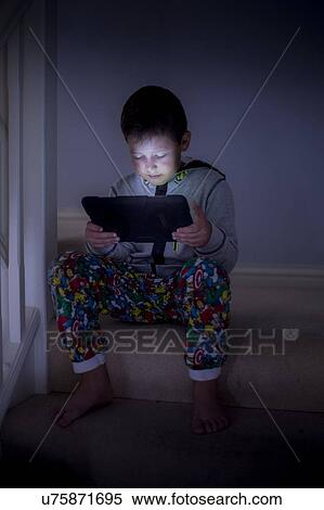 Stock Photography - Boy using a digital tablet in the dark. Fotosearch
