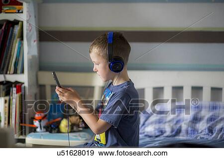 Stock Photo - Boy wearing headphones using device. Fotosearch