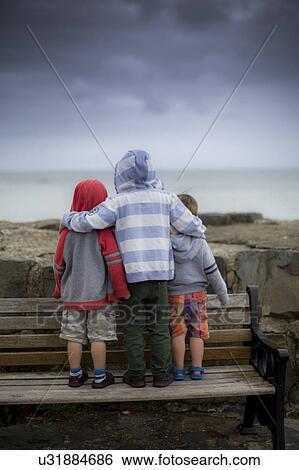 Stock Photograph - Boys standing on bench. Fotosearch