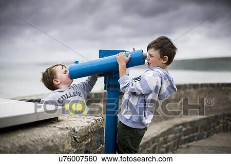 Stock Image - Boys using coin operated telescopes. Fotosearch