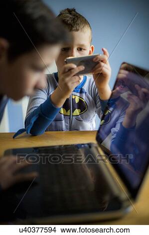Boys using smartphone and laptop View Large Photo Image Picture - Boys using smartphone and laptop. Fotosearch