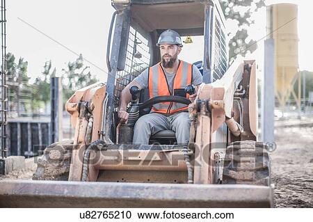 Stock Image - Builder driving excavator on construction site. Fotosearch