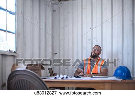 Builder sitting at desk in portable cabin View Large Photo Image Stock Photo - Builder sitting at desk in portable cabin. Fotosearch