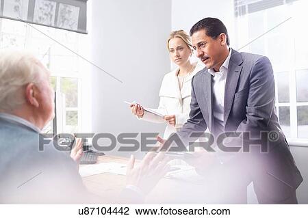 Stock Image - Business man and business woman in office having discussion with senior customer. Fotosearch