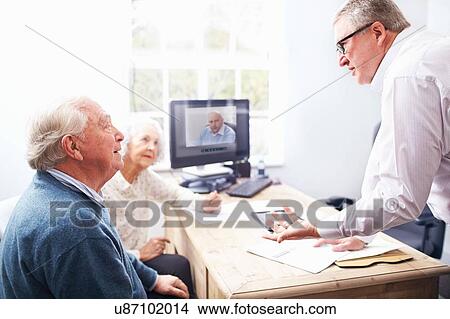Picture - Business man in office having discussion with senior couple. Fotosearch