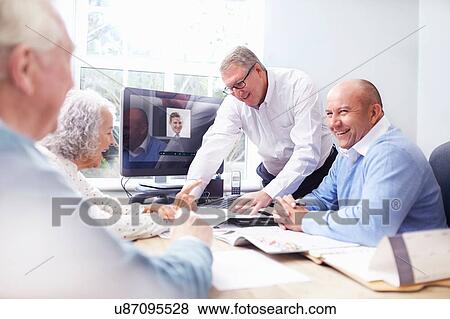 Stock Photo - Business men in office having discussion with senior couple. Fotosearch