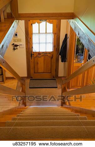 Stock Photography - Carpeted wooden stairs and main entrance inside a Canadian cottage style log home. Fotosearch