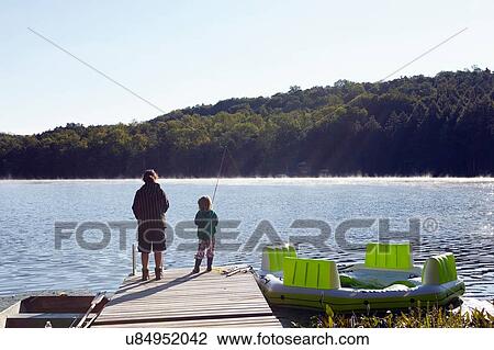 Stock Image - "Children fishing on pier by lake, New Milford, Pennsylvania, US". Fotosearch
