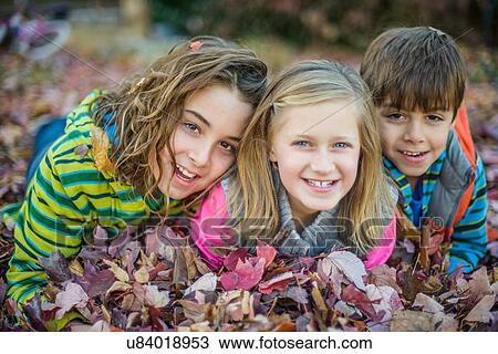 Children lying on autumn leaves in garden View Large Photo Image Stock Image - Children lying on autumn leaves in garden. Fotosearch