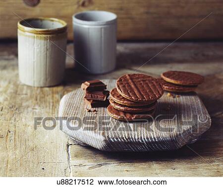 Stock Image - Chocolate digestive biscuits on vintage wooden cutting board. Fotosearch