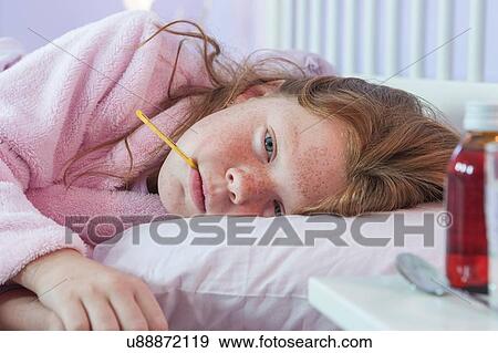 Close up of girl lying in bed with thermometer in her mouth View Large Photo Image Stock Photo - Close up of girl lying in bed with thermometer in her mouth. Fotosearch