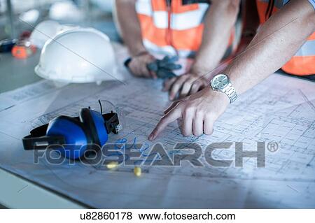 Stock Photo - Close up of male hand pointing on blueprint in construction site. Fotosearch