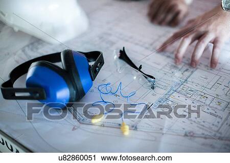 Stock Image - Close up of male hands on blueprint in construction site. Fotosearch
