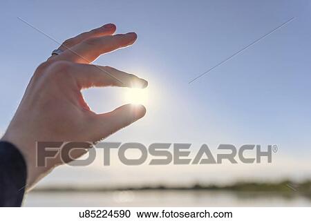 Close up of mans hand with sun between fingers against blue sky View Large Photo Image Stock Image - Close up of mans hand with sun between fingers against blue sky. Fotosearch
