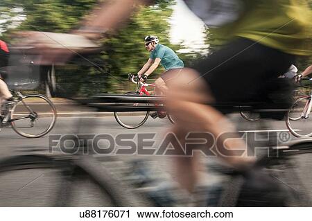 Stock Image - Close up of racing cyclists speeding on urban road in racing cycle race. Fotosearch