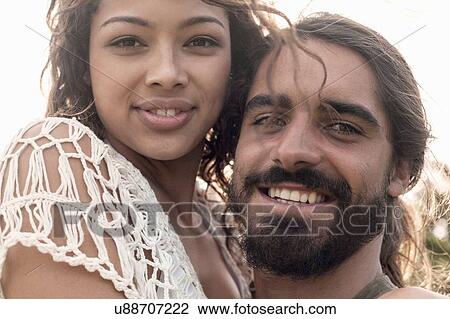 Close up portrait of young couple hugging looking at camera smiling View Large Photo Image Stock Image - Close up portrait of young couple hugging looking at camera smiling. Fotosearch