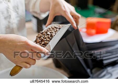 Stock Photograph - Coffee seller filling bag with coffee beans. Fotosearch