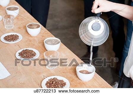 Stock Image - Coffee seller pouring hot water into cup of coffee. Fotosearch