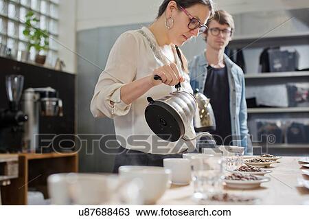 Stock Image - Coffee taster pouring hot water into cup of coffee. Fotosearch