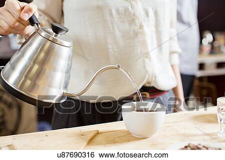 Stock Photograph - Coffee taster pouring hot water into cup of coffee. Fotosearch
