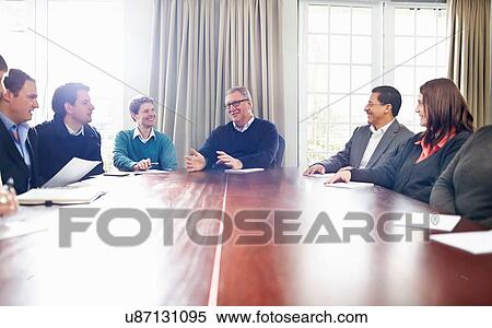 Stock Photography - Colleagues in conference room sitting at table having a meeting. Fotosearch