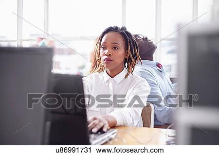 Stock Image - Colleagues in office at computer looking overworked. Fotosearch