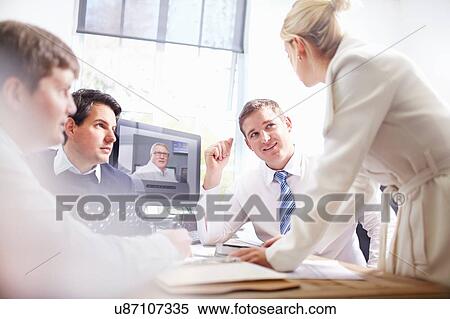 Colleagues in office at desk making video call, having discussion View Large Photo Image Stock Photography - Colleagues in office at desk making video call, having discussion. Fotosearch