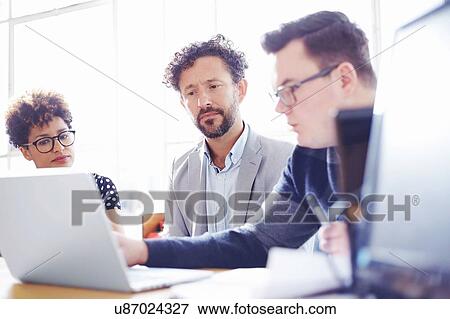 Colleagues in office looking at laptop View Large Photo Image Stock Photo - Colleagues in office looking at laptop. Fotosearch