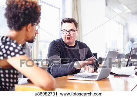 Colleagues in office using laptop chatting View Large Photo Image Stock Image - Colleagues in office using laptop chatting. Fotosearch