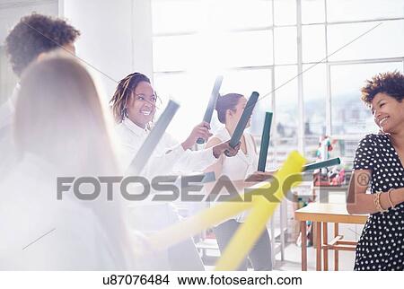 Colleagues in team building task, holding tubes smiling View Large Photo Image Picture - Colleagues in team building task, holding tubes smiling. Fotosearch