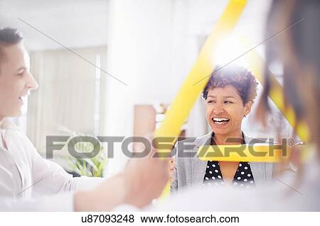 Stock Photo - Colleagues in team building task, holding yellow tubes smiling. Fotosearch