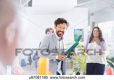 Stock Photography - Colleagues in team building task, holding tubes smiling. Fotosearch