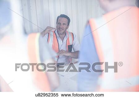 Stock Photography - Construction foreman and builders meeting at desk in portable cabin. Fotosearch