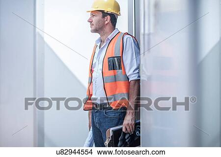 Construction foreman looking out from doorway of portable cabin on construction site View Large Photo Image Picture - Construction foreman looking out from doorway of portable cabin on construction site. Fotosearch