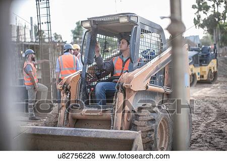 Construction worker driving excavator on construction site View Large Photo Image Stock Photo - Construction worker driving excavator on construction site. Fotosearch
