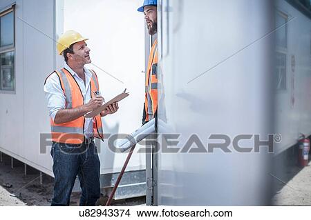 Picture - Construction worker talking to foreman from doorway of construction cabin. Fotosearch