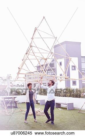 Couple arms raised, carrying wooden structure View Large Photo Image Stock Photography - Couple arms raised, carrying wooden structure. Fotosearch