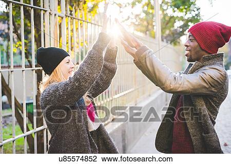 Couple doing high five beside steel fence View Large Photo Image Stock Image - Couple doing high five beside steel fence. Fotosearch