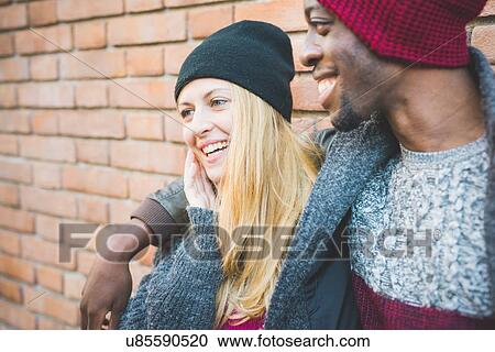Stock Image - Couple enjoying quiet moment against brick wall. Fotosearch
