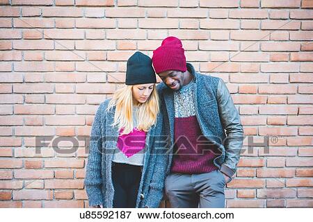 Couple enjoying quiet moment against brick wall View Large Photo Image Stock Photo - Couple enjoying quiet moment against brick wall. Fotosearch