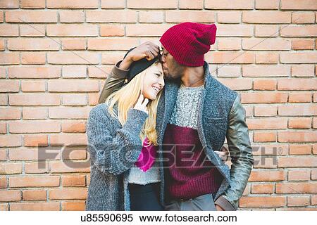 Stock Photography - Couple enjoying quiet moment against brick wall. Fotosearch